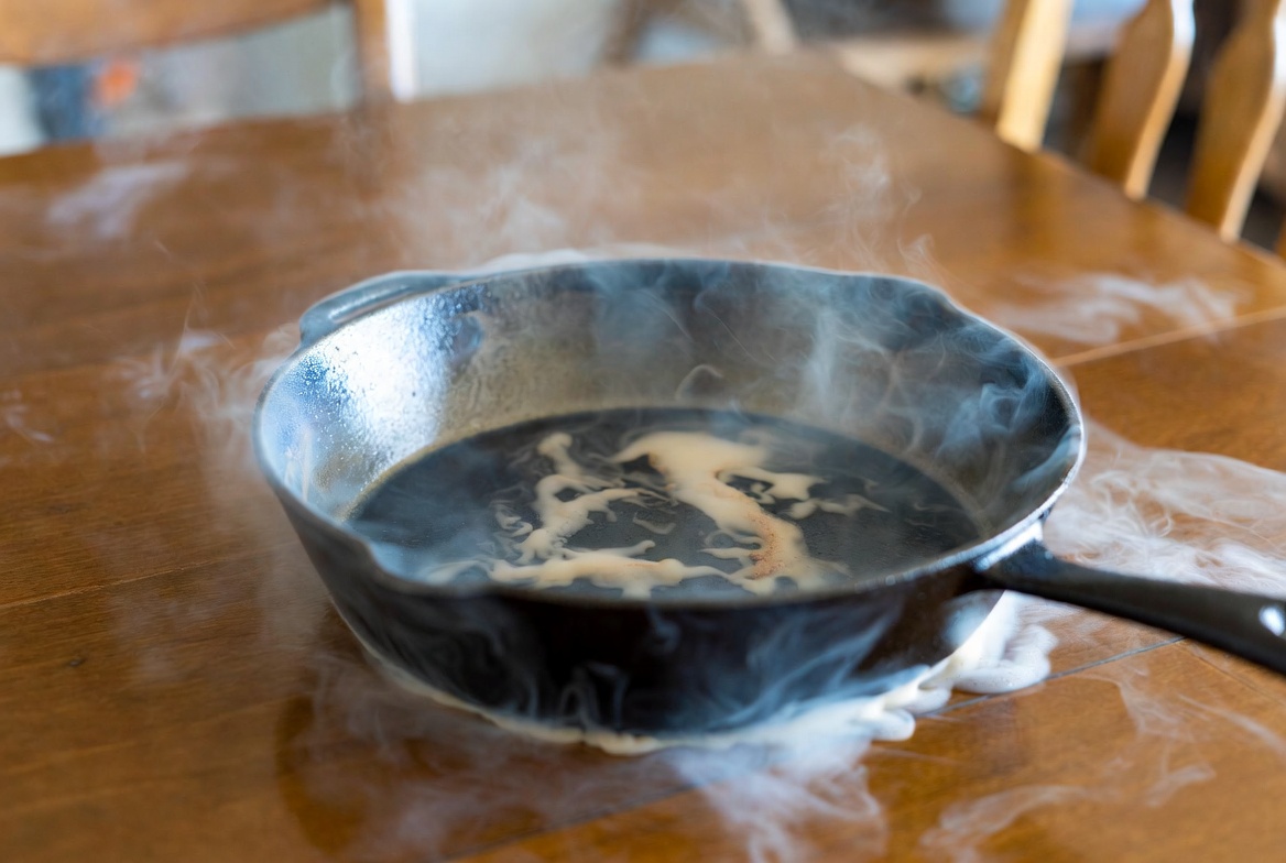 Hot cast iron pan causing white heat marks and rings on wooden dining table